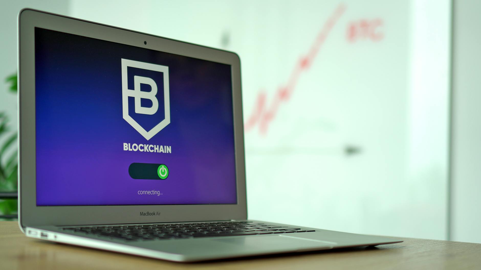 Laptop screen showing a blockchain logo and connecting status.