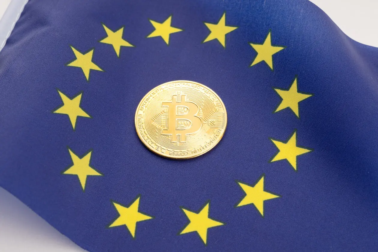 Bitcoin coin placed on a European Union flag with yellow stars.