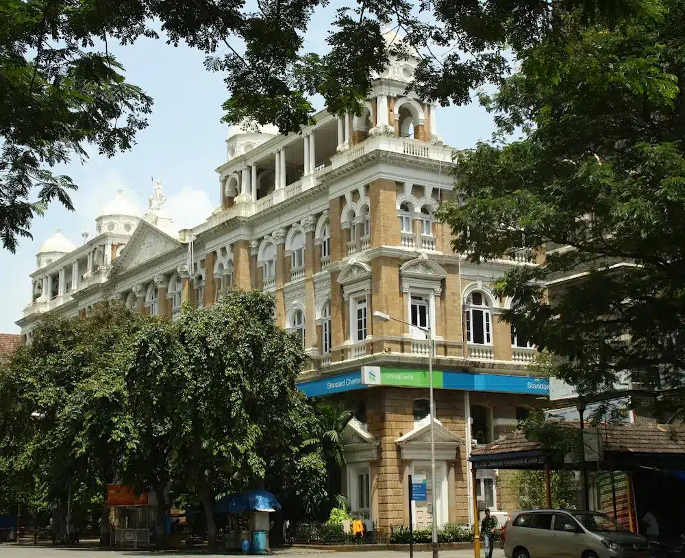 The Standard Chartered bank building with greenery and street view.