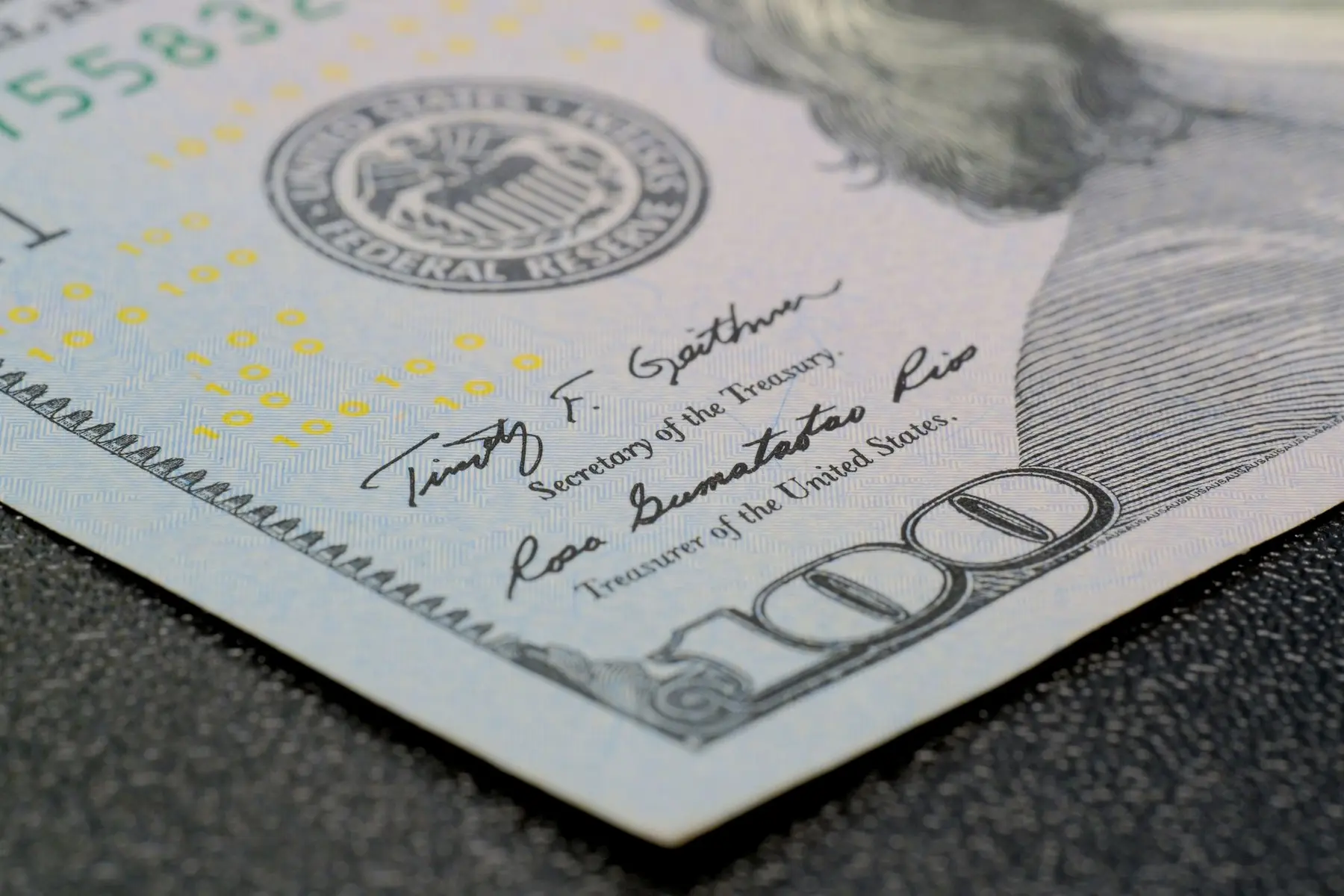Close-up of a US 100 dollar bill showing the Federal Reserve seal and signatures