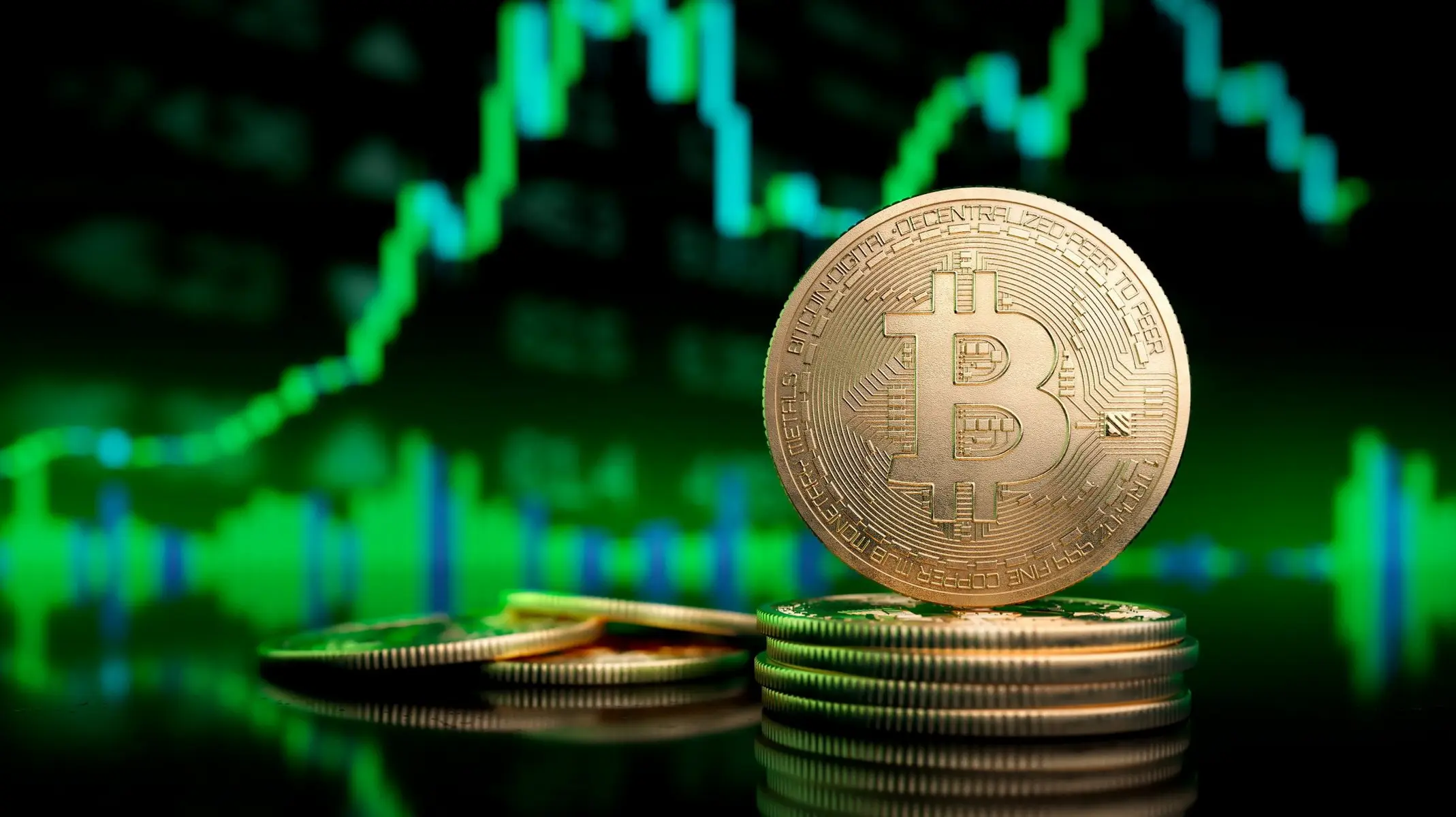 A stack of gold Bitcoin coins in front of a blurred green candlestick trading chart on a dark background