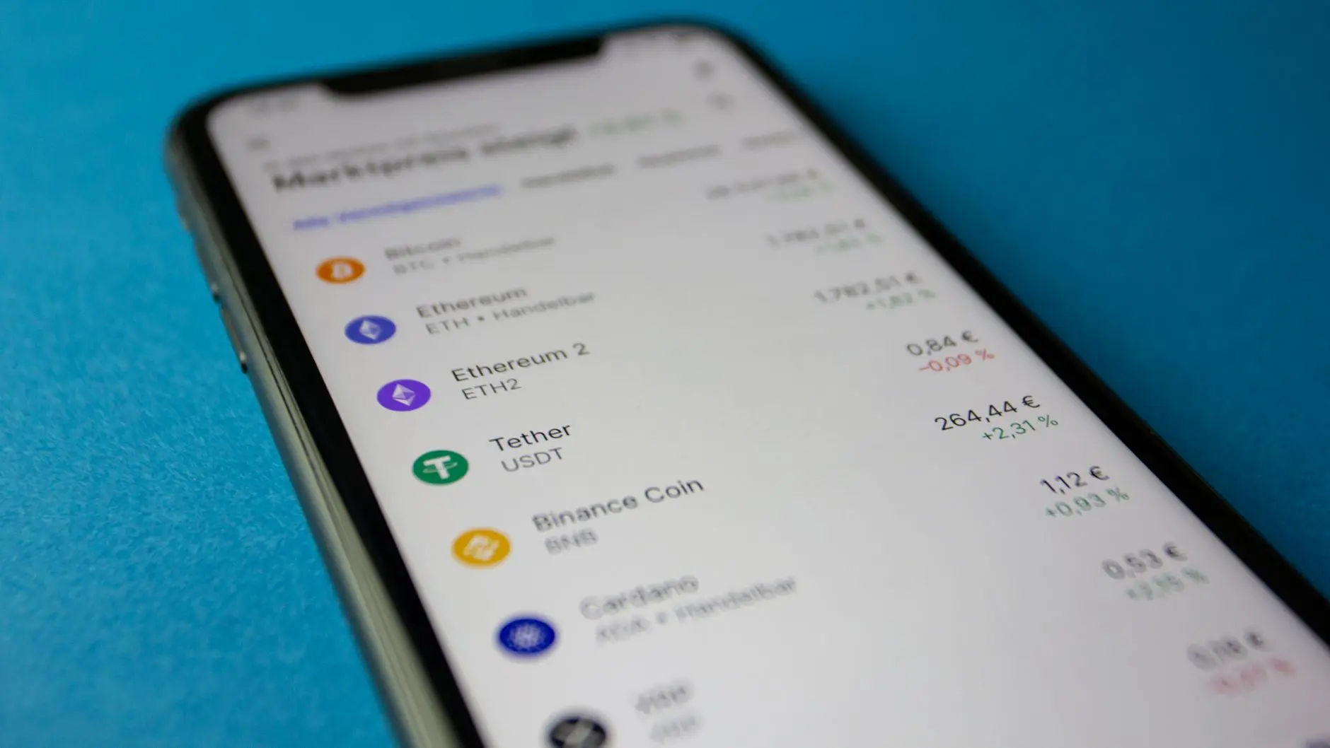 Close-up of a smartphone screen displaying a cryptocurrency portfolio with Bitcoin, Ethereum, and Tether listed.