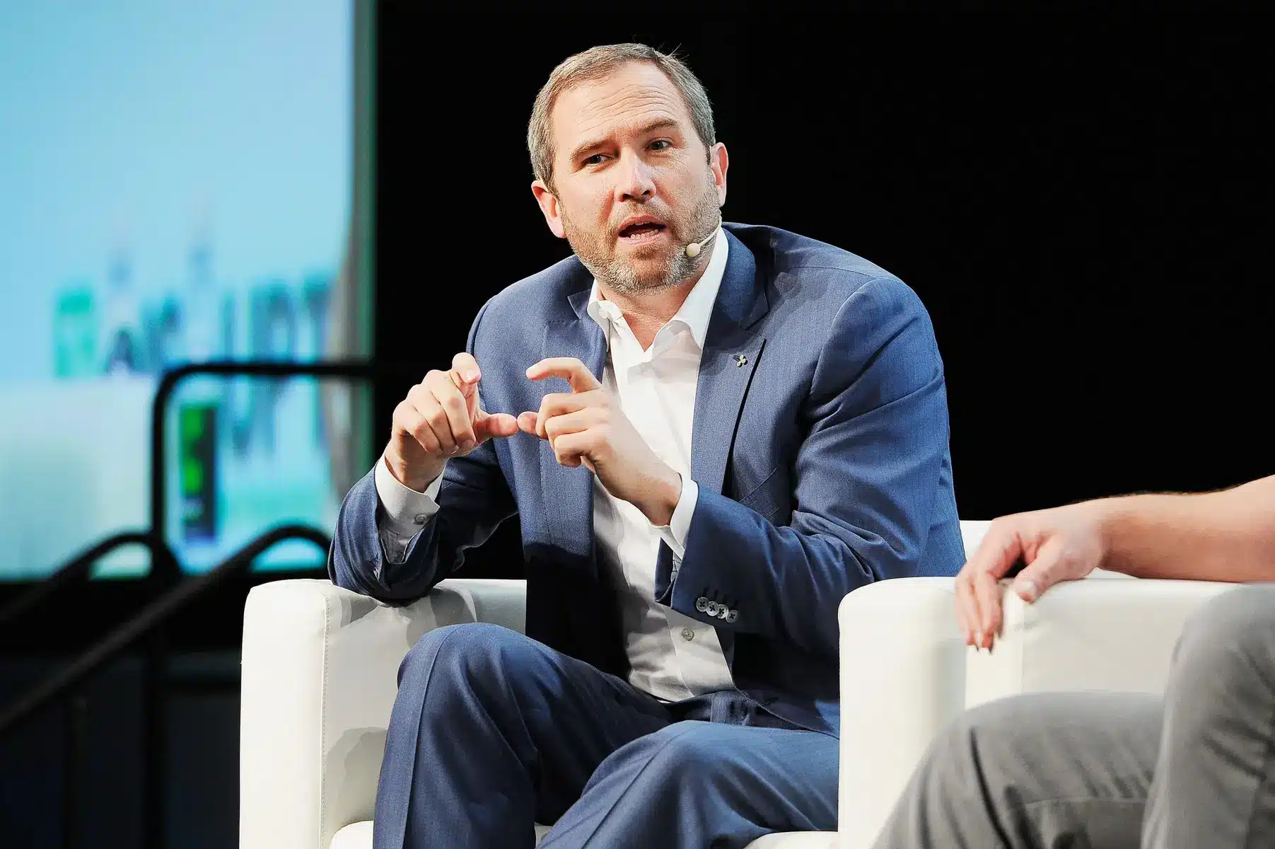 Brad Garlinghouse, Ripple CEO, wearing a blue suit and speaking during a panel discussion.