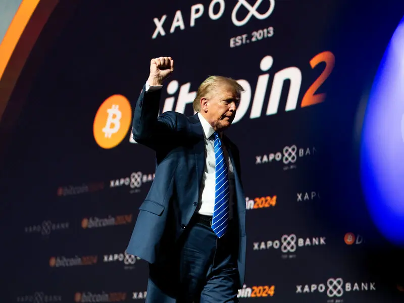 Donald Trump raising his fist in front of a Bitcoin 2024 and Xapo Bank backdrop