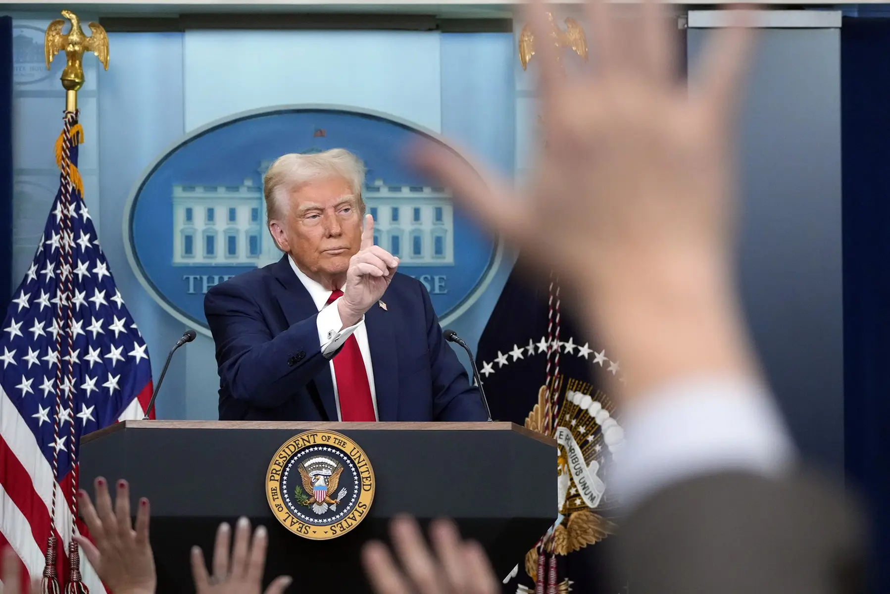 Donald Trump speaking from a podium with the Presidential seal in front of a White House backdrop.