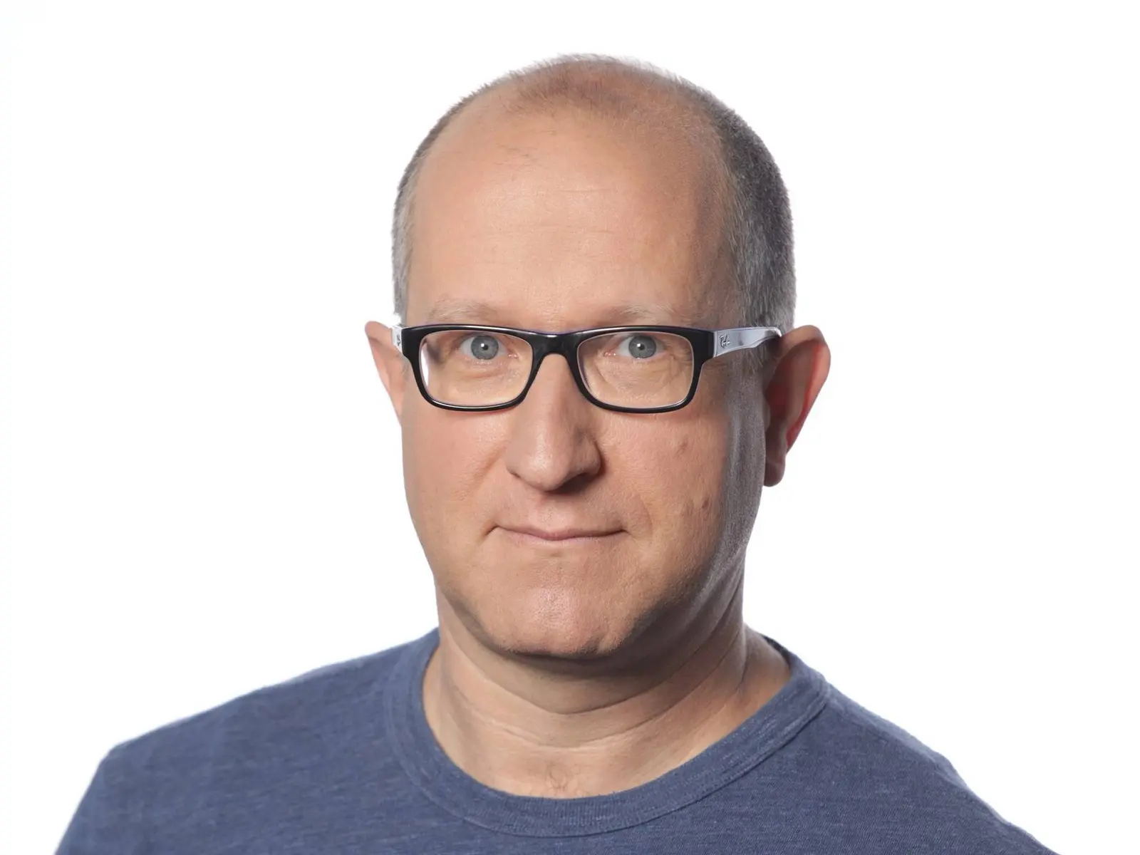 Headshot of Eli Ben-Sasson wearing black-rimmed glasses and a blue t-shirt against a white background.