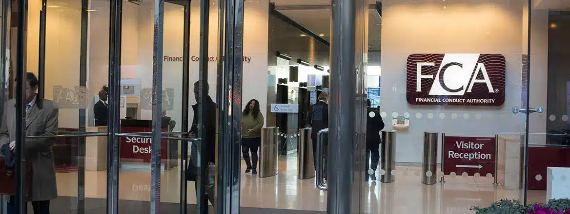Entrance to the Financial Conduct Authority office in London, featuring the FCA logo on the wall and security personnel.