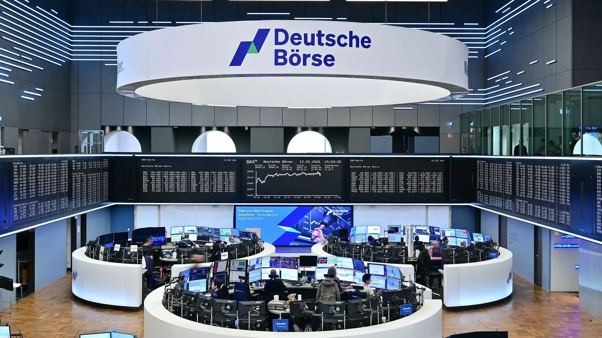 Wide shot of the Deutsche Börse trading floor in Frankfurt with computer terminals and large stock data screens.