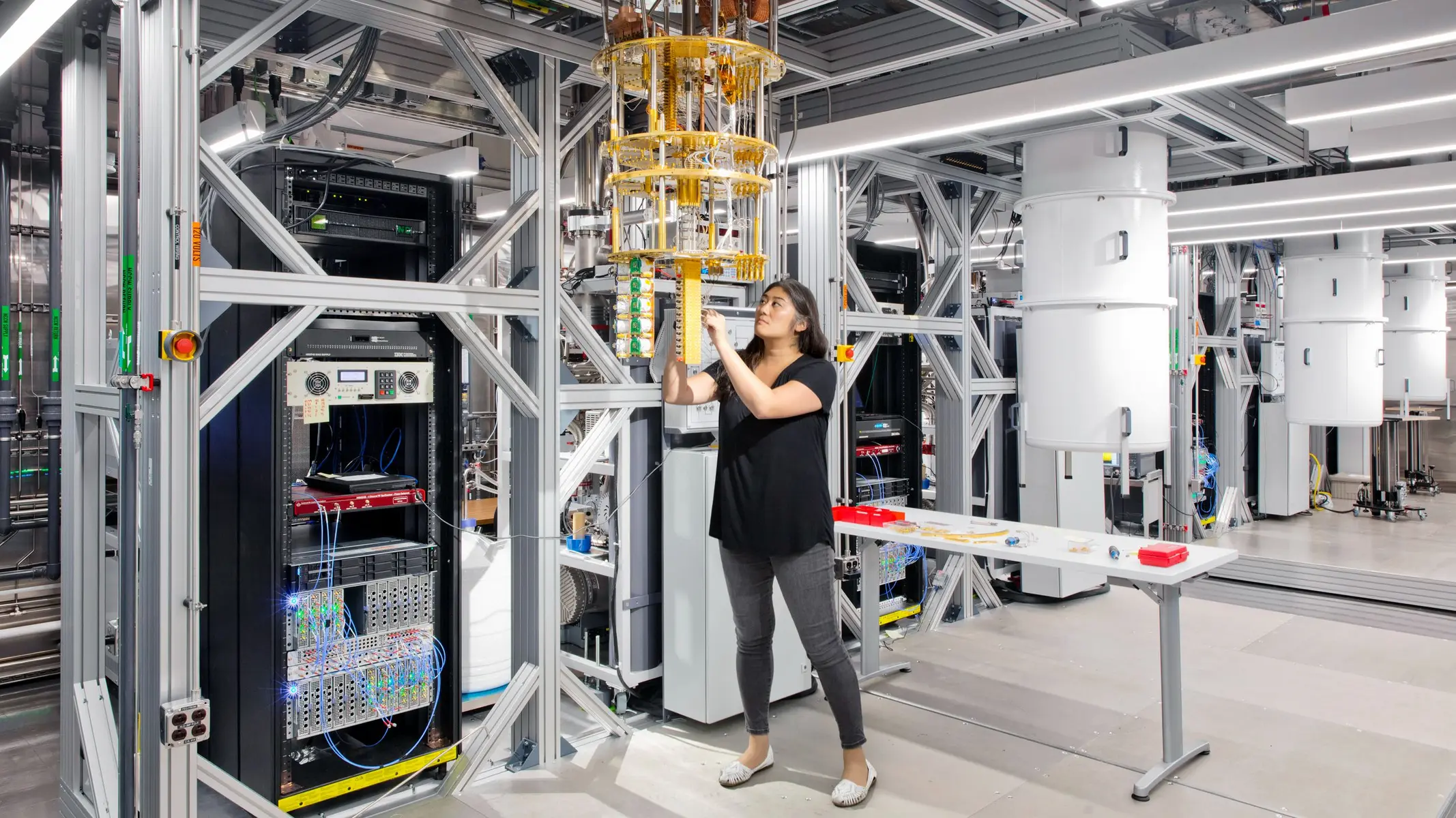 A scientist adjusting a gold-plated dilution refrigerator in a quantum computing laboratory.