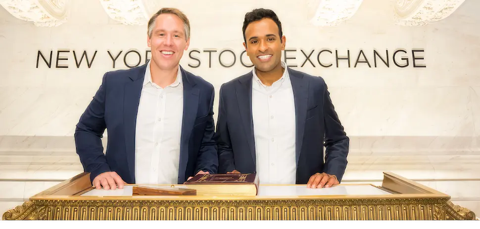 Vivek Ramaswamy and a colleague standing behind a podium at the New York Stock Exchange