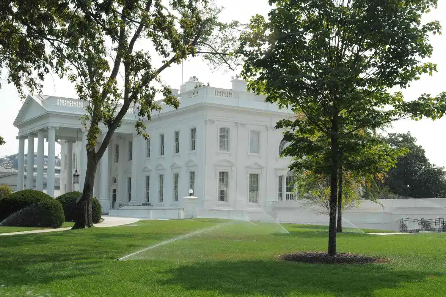 Exterior view of the White House in Washington DC with green lawns and trees