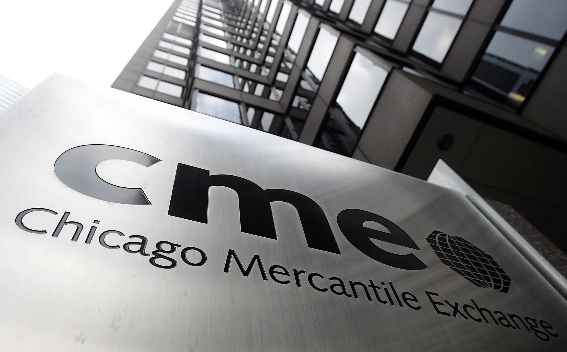 Close-up of the Chicago Mercantile Exchange CME Group sign on a brushed metal surface with a building in the background