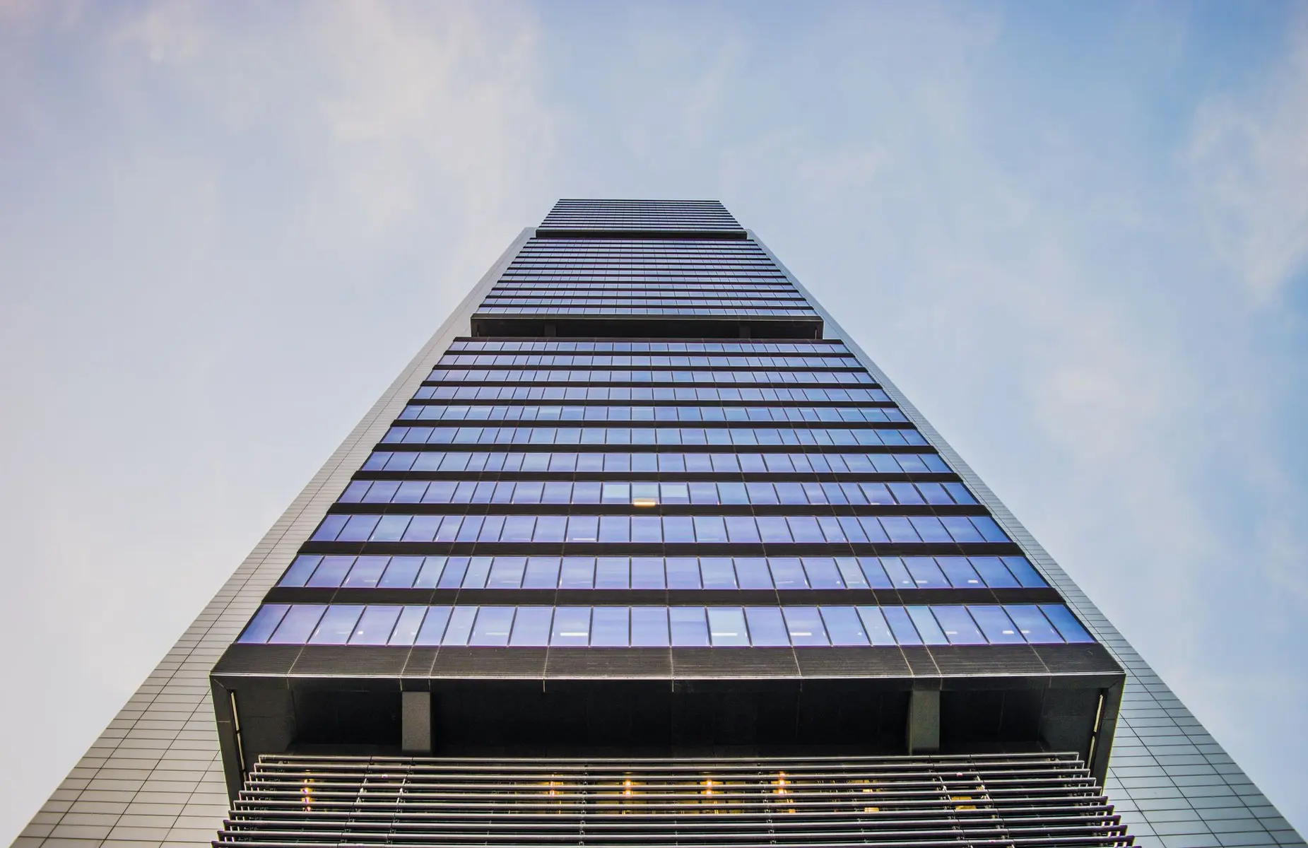Low-angle shot of the modern glass and steel Goldman Sachs headquarters building tower against a blue sky