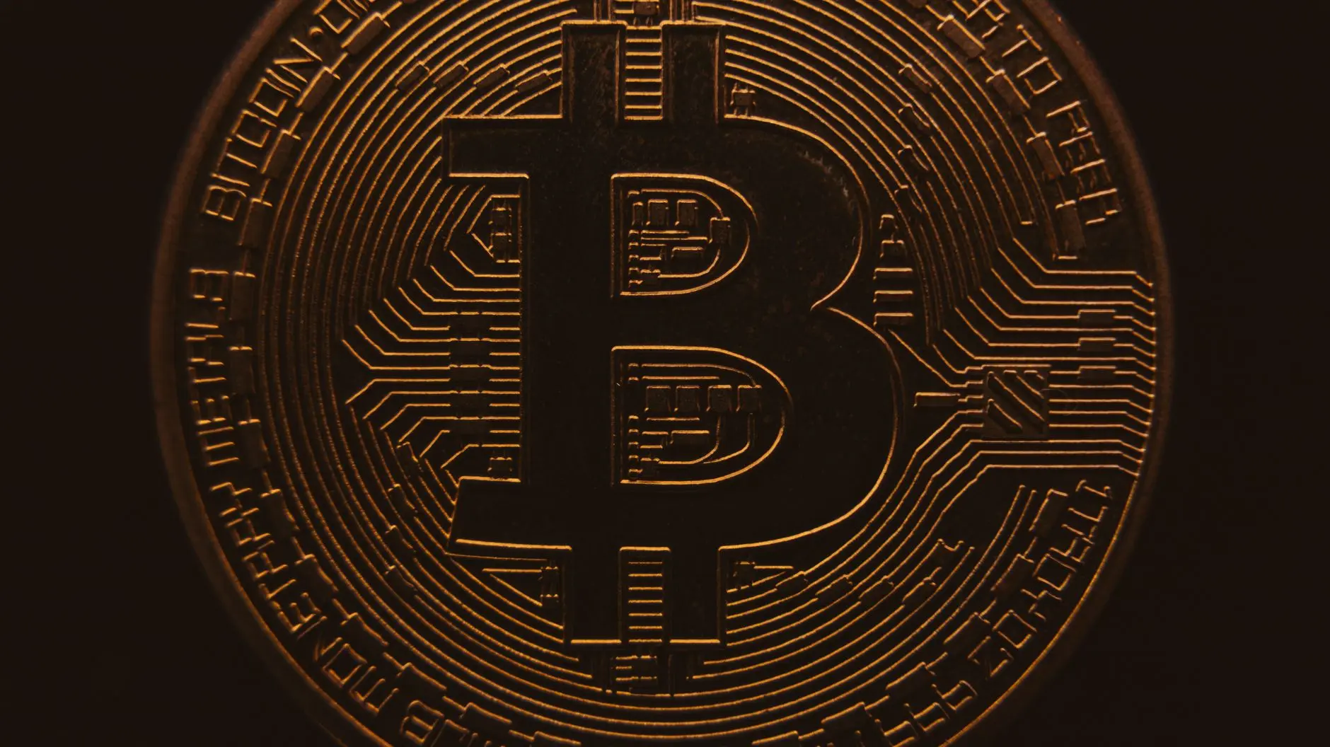Close-up of a physical gold-colored Bitcoin coin with intricate circuit patterns