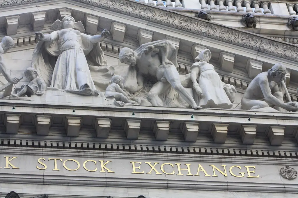 Die Fassade der New York Stock Exchange mit goldenem Schriftzug und klassizistischen Skulpturen.