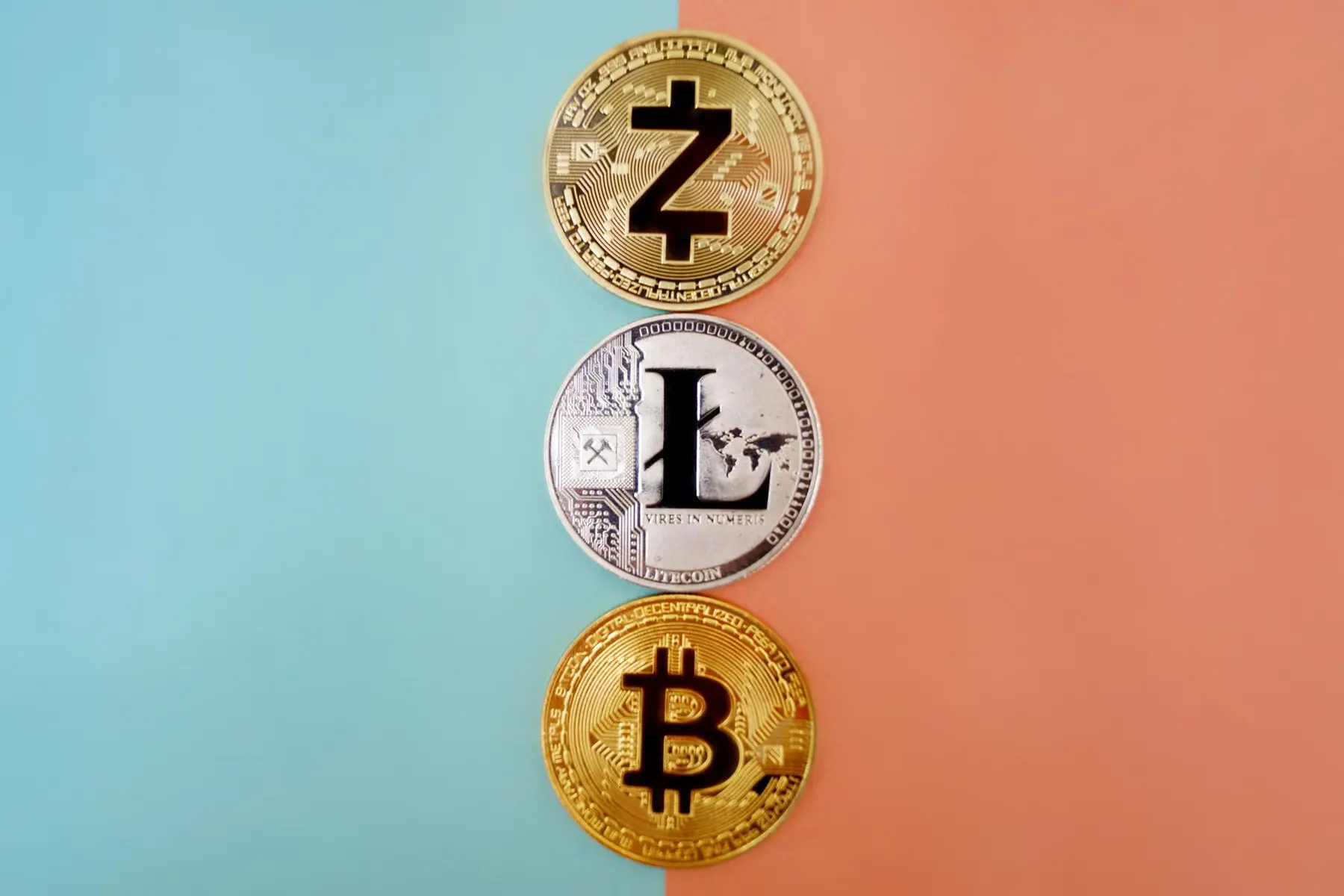 Three cryptocurrency coins featuring Zcash, Litecoin, and Bitcoin symbols stacked vertically on a split blue and orange background.