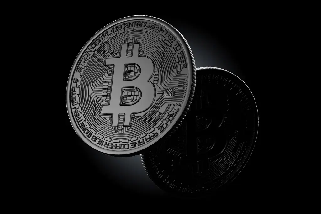 Zwei physische Bitcoin-Münzen mit dem markanten B-Symbol auf schwarzem Hintergrund.