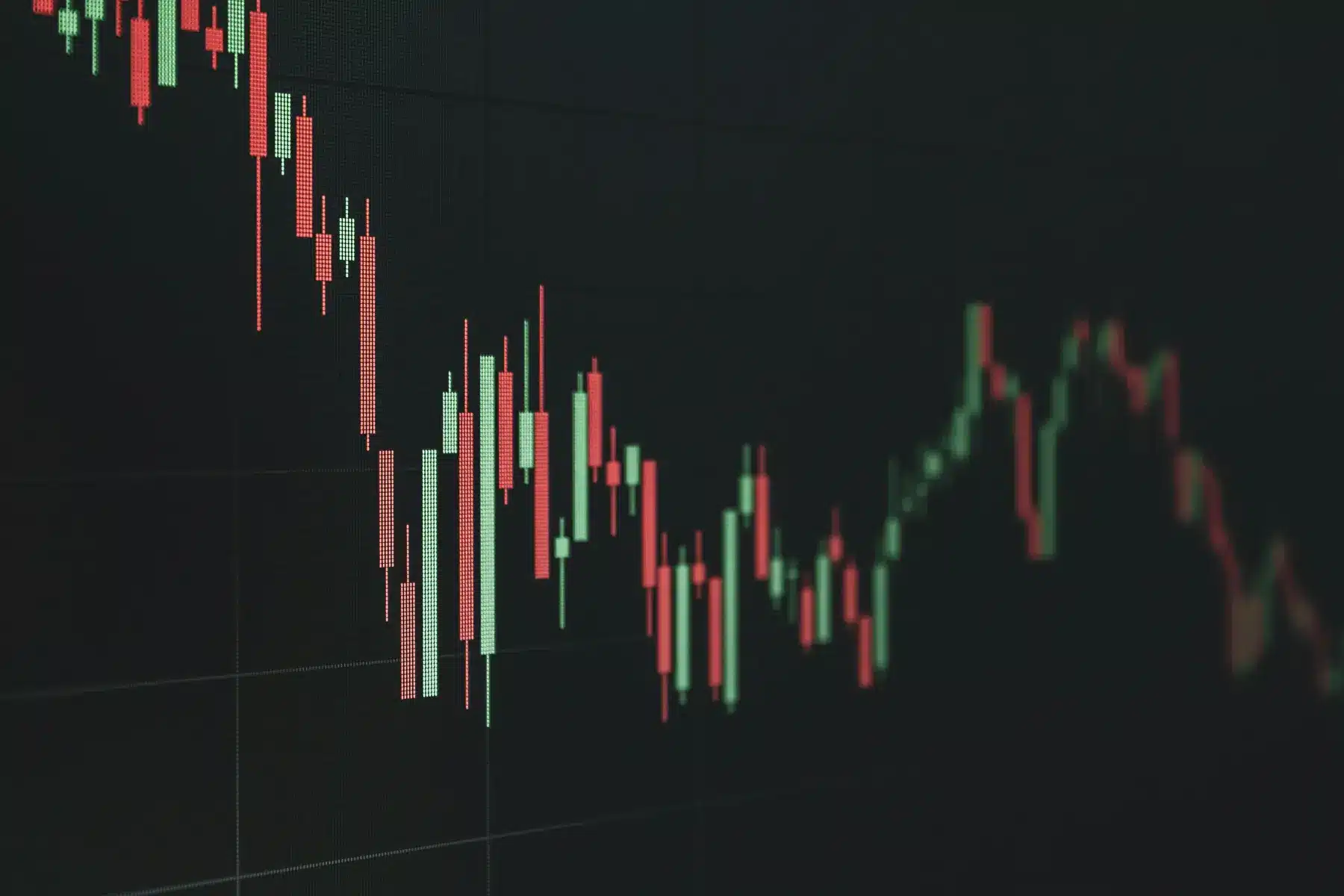 Ein Candlestick-Chart mit roten und grünen Kerzen auf einem dunklen Bildschirm, der einen fallenden Trend zeigt.