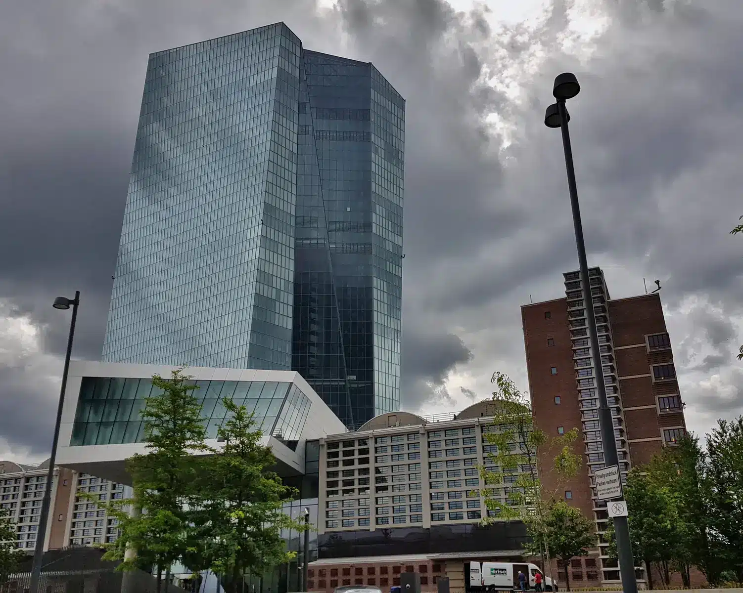 Das moderne Glasgebäude der Europäischen Zentralbank in Frankfurt am Main unter einem bewölkten Himmel.