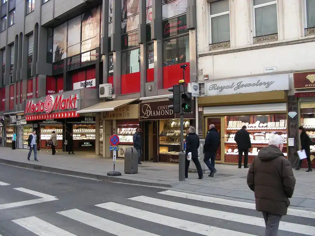 Außenansicht einer MediaMarkt-Filiale in einer Einkaufsstraße mit Passanten und einem Zebrastreifen im Vordergrund.
