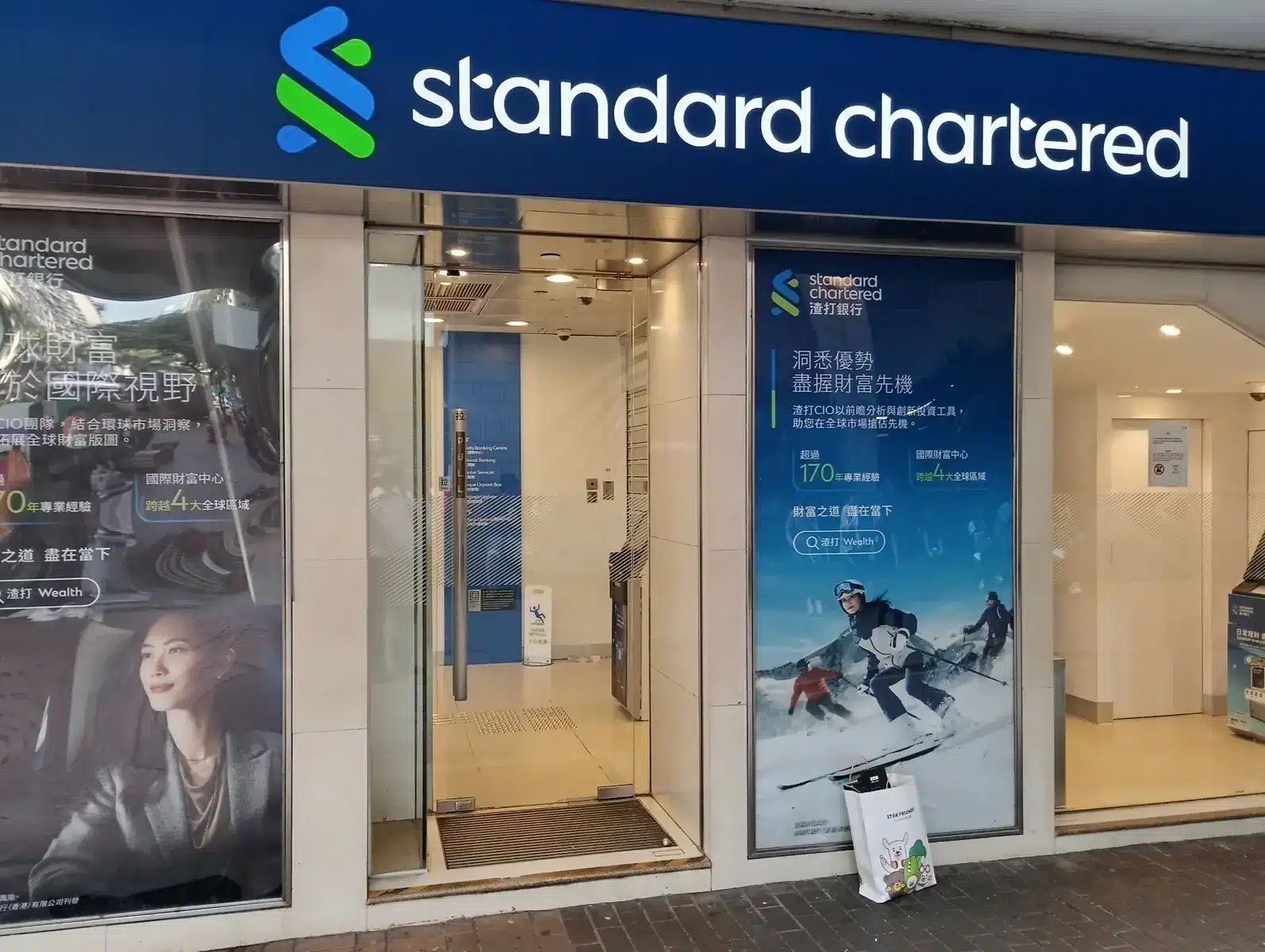 Die Außenansicht einer Standard Chartered Bankfiliale mit dem Firmenlogo über dem Eingang.