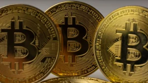 Three gold Bitcoin coins displayed closely together.
