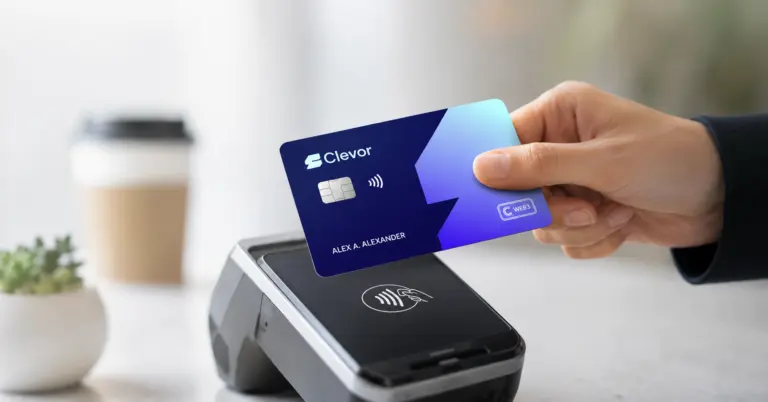 A hand holding a blue Clevor Web3 crypto debit card over a contactless payment terminal